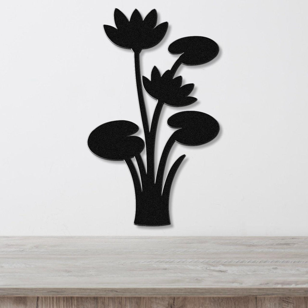 Black metal wall art featuring a lotus water lily silhouette with cutout flowers and leaves, mounted on a white wall above a wooden surface.