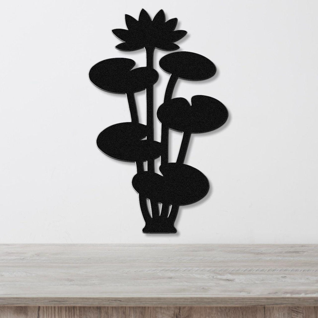 Black metal lotus water lily wall art with layered flower and leaf cutouts, mounted on a white wall above a wooden surface.