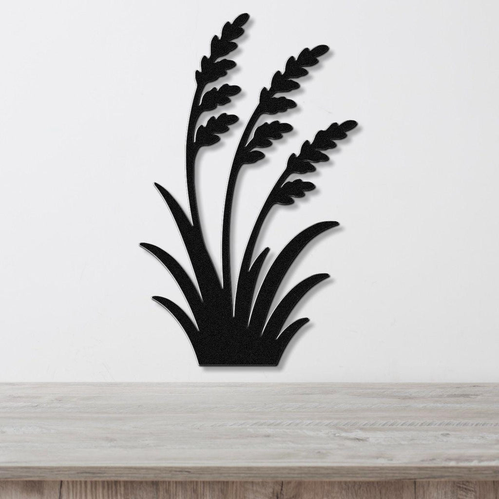 Black metal wall art in a wild grass silhouette design, mounted on a white wall above a light wood surface.
