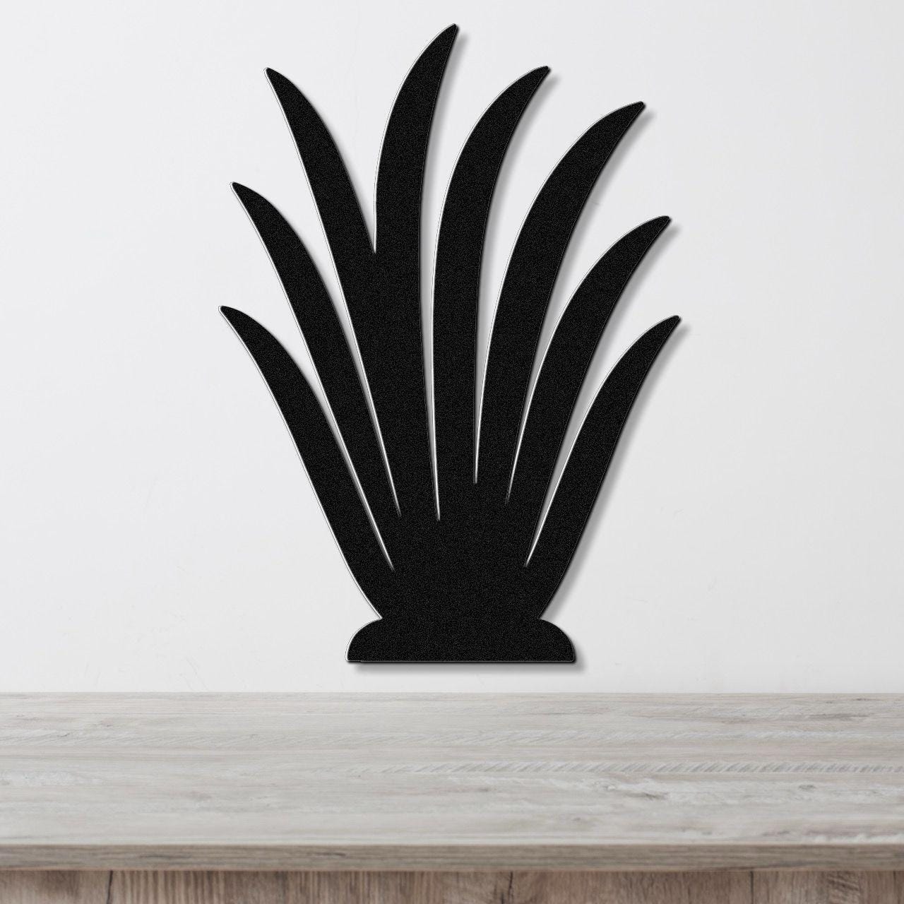 Black metal wall art in a silhouette of a spiky plant, mounted on a white wall above a light wood surface.