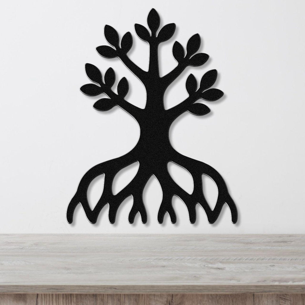 Black metal wall art in the shape of a tree with visible roots and leafy branches, mounted on a white wall above a wooden surface.