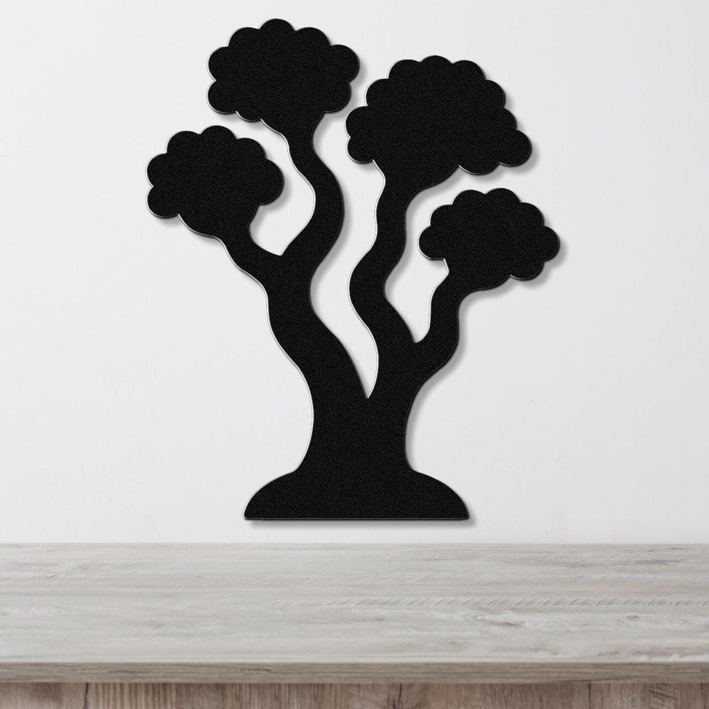 Black metal wall art in a stylized tree silhouette with three rounded canopies and curved trunks, mounted on a white wall above a light wood surface.