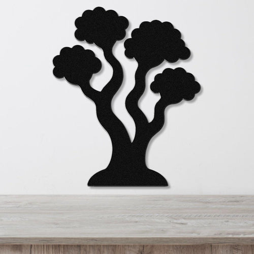 Black metal wall art in a stylized tree silhouette with three rounded canopies and curved trunks, mounted on a white wall above a light wood surface.