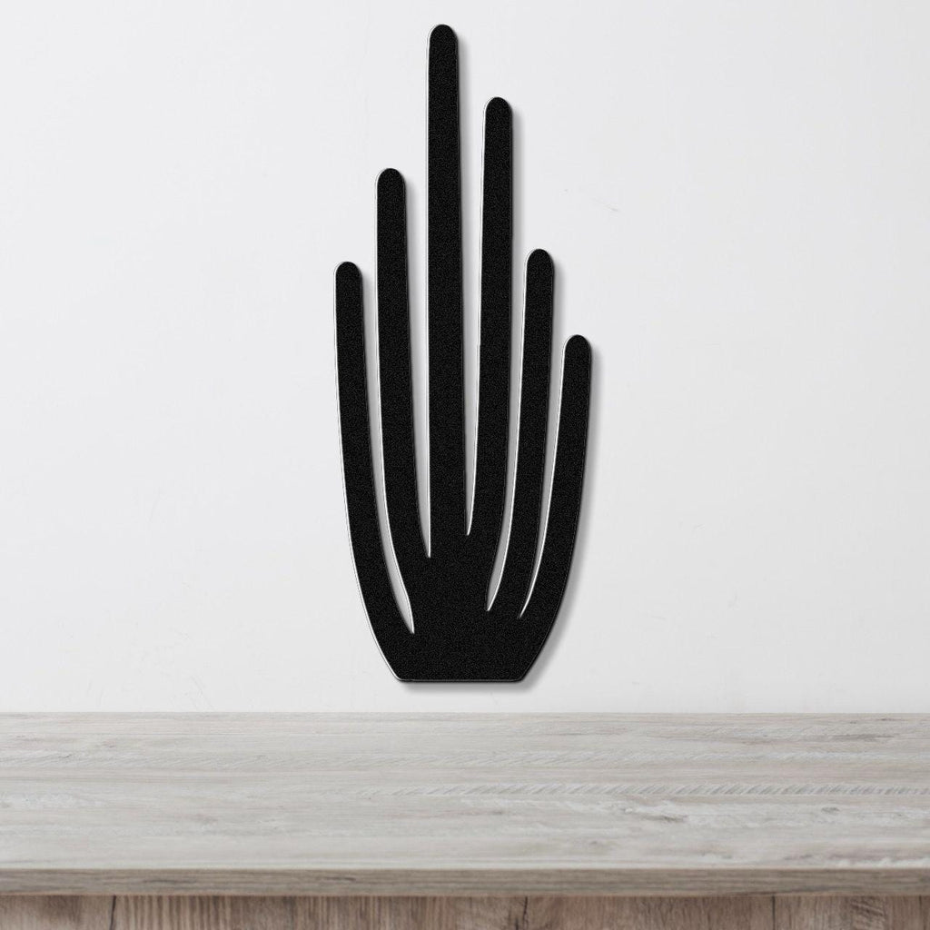 Black metal wall art cutout of an organ pipe cactus with vertical spines, mounted on a white wall above a light wood surface.