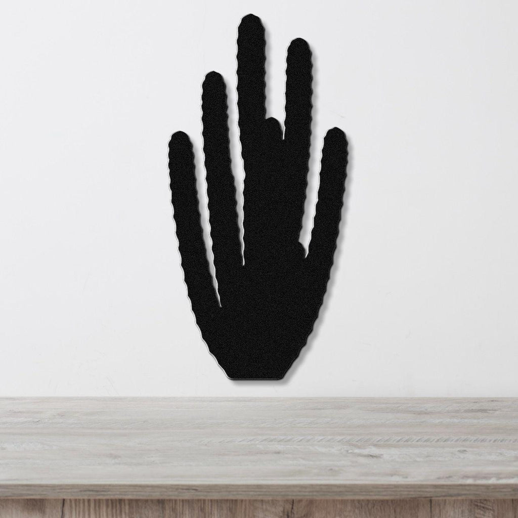 Black metal wall art cutout of an organ pipe cactus with vertical spines, mounted on a white wall above a light wood surface.