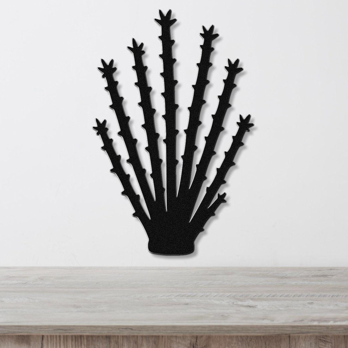 Black metal ocotillo wall art with spiky branch cutouts, mounted on a white wall above a light wood counter.