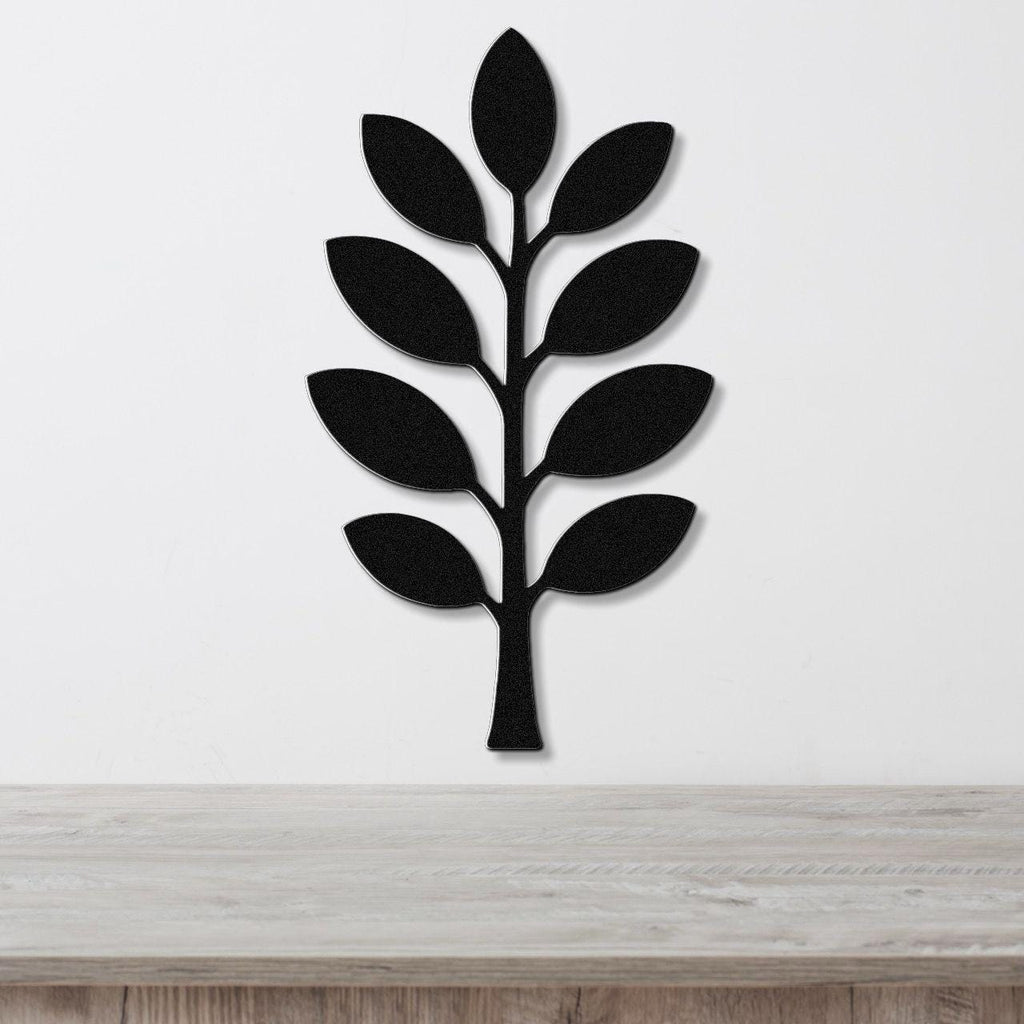 Black metal wall art in the shape of an olive branch with leaf cutouts, mounted on a white wall above a light wood surface.