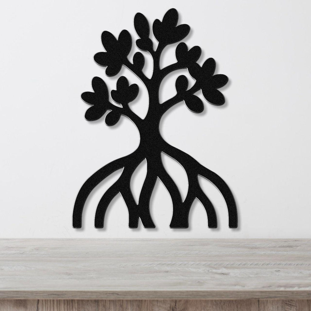 Black metal wall art cutout of a mangrove tree with visible roots and leafy branches, mounted on a white wall above a wooden surface.