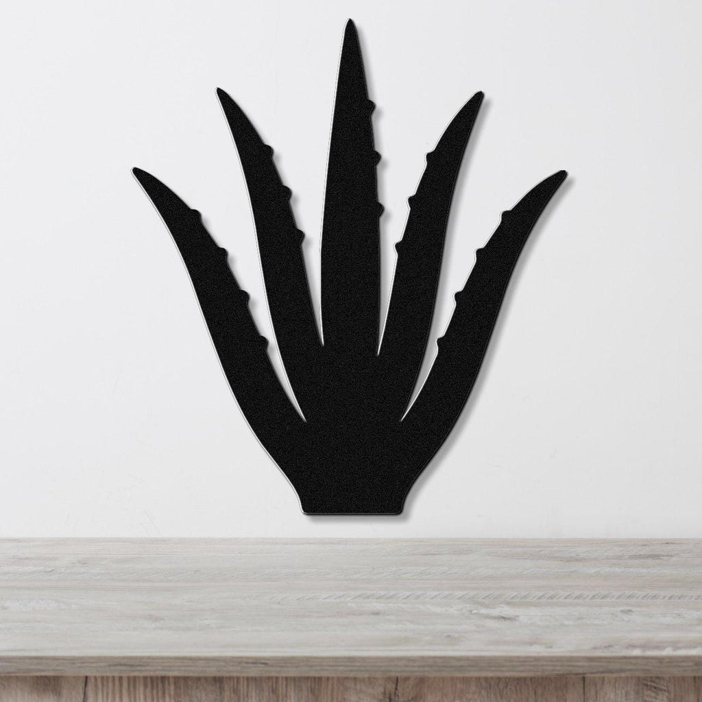 Black metal agave wall art with spiky leaf cutouts, mounted on a white wall above a light wood countertop.