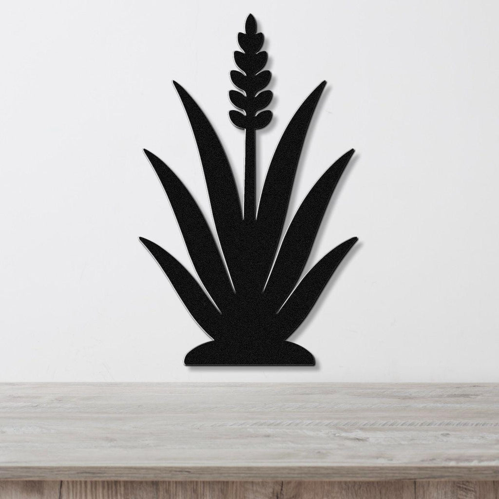 Black metal agave wall art with a central flower spike and leaf cutouts, mounted on a white wall above a light wood surface.