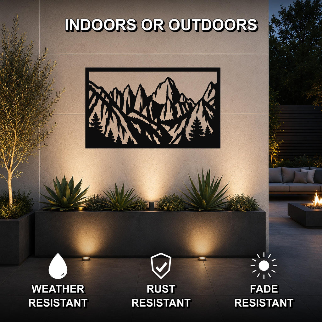 Black metal wall art with a mountain and tree silhouette cutout, mounted on an outdoor wall above a planter in a patio setting.