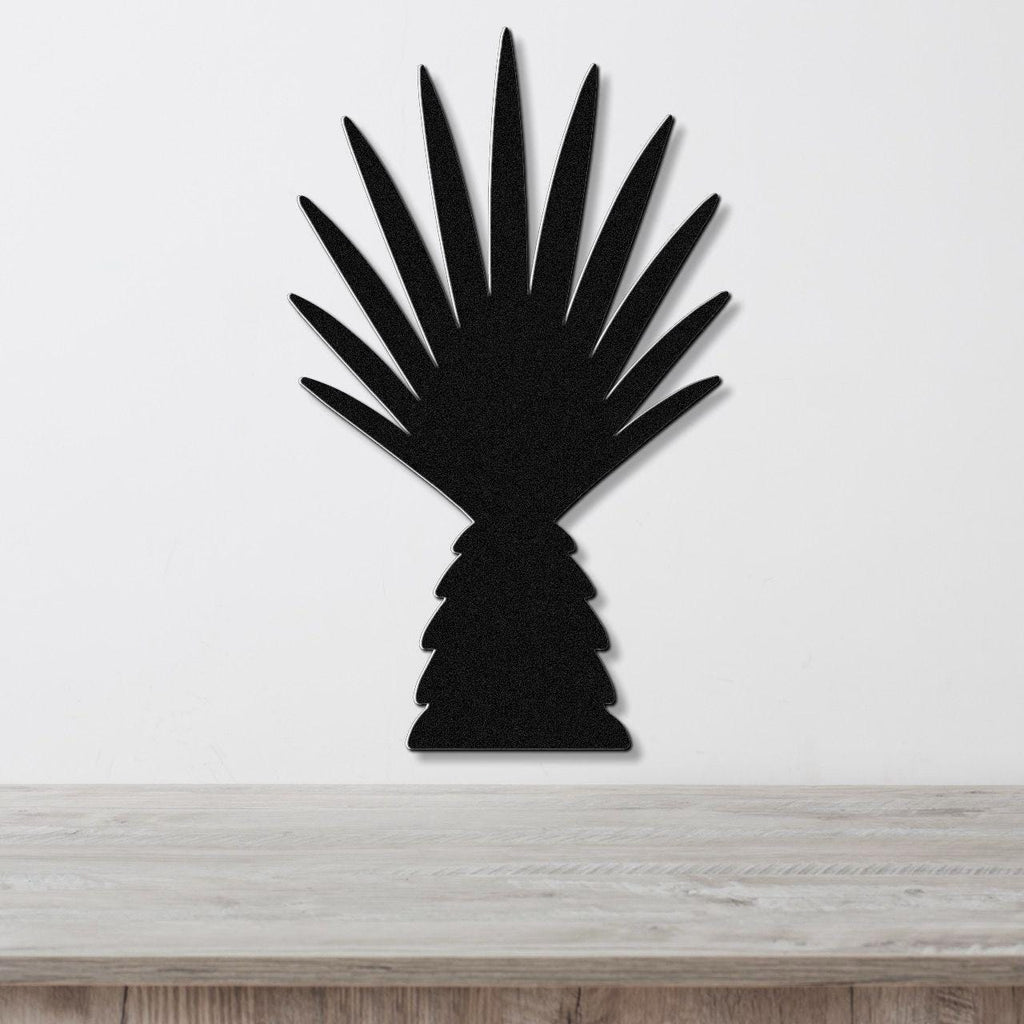 Black metal wall art cutout of a fan palm tree with radiating fronds, mounted on a white wall above a light wood surface.