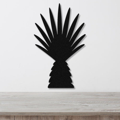 Black metal wall art cutout of a fan palm tree with radiating fronds, mounted on a white wall above a light wood surface.