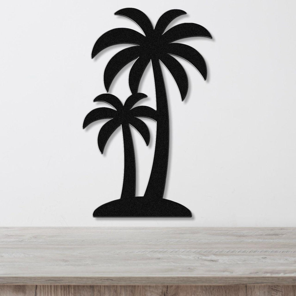 Black metal wall art featuring a silhouette of two palm trees with layered fronds, mounted on a white wall above a light wood surface.
