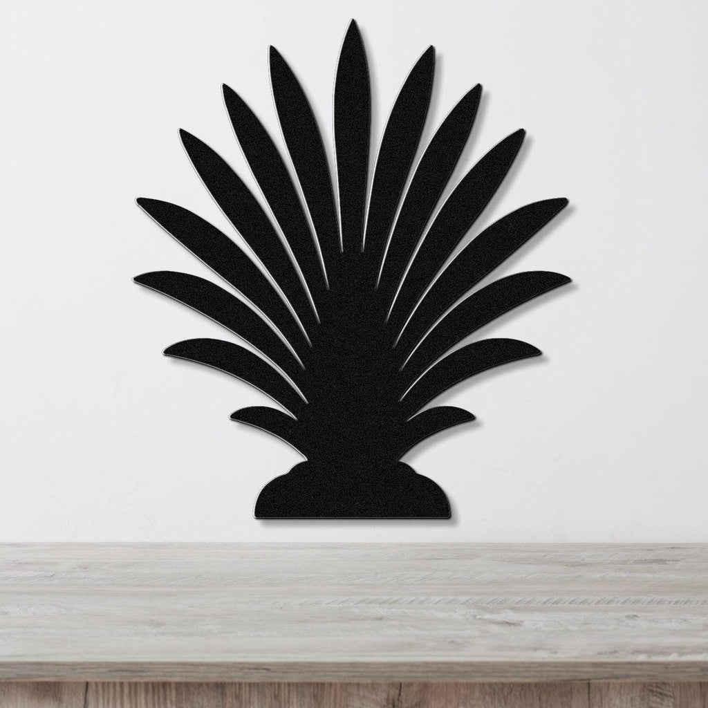 Black metal palm tree wall art with layered leaf cutouts, mounted on a white wall above a light wood countertop.
