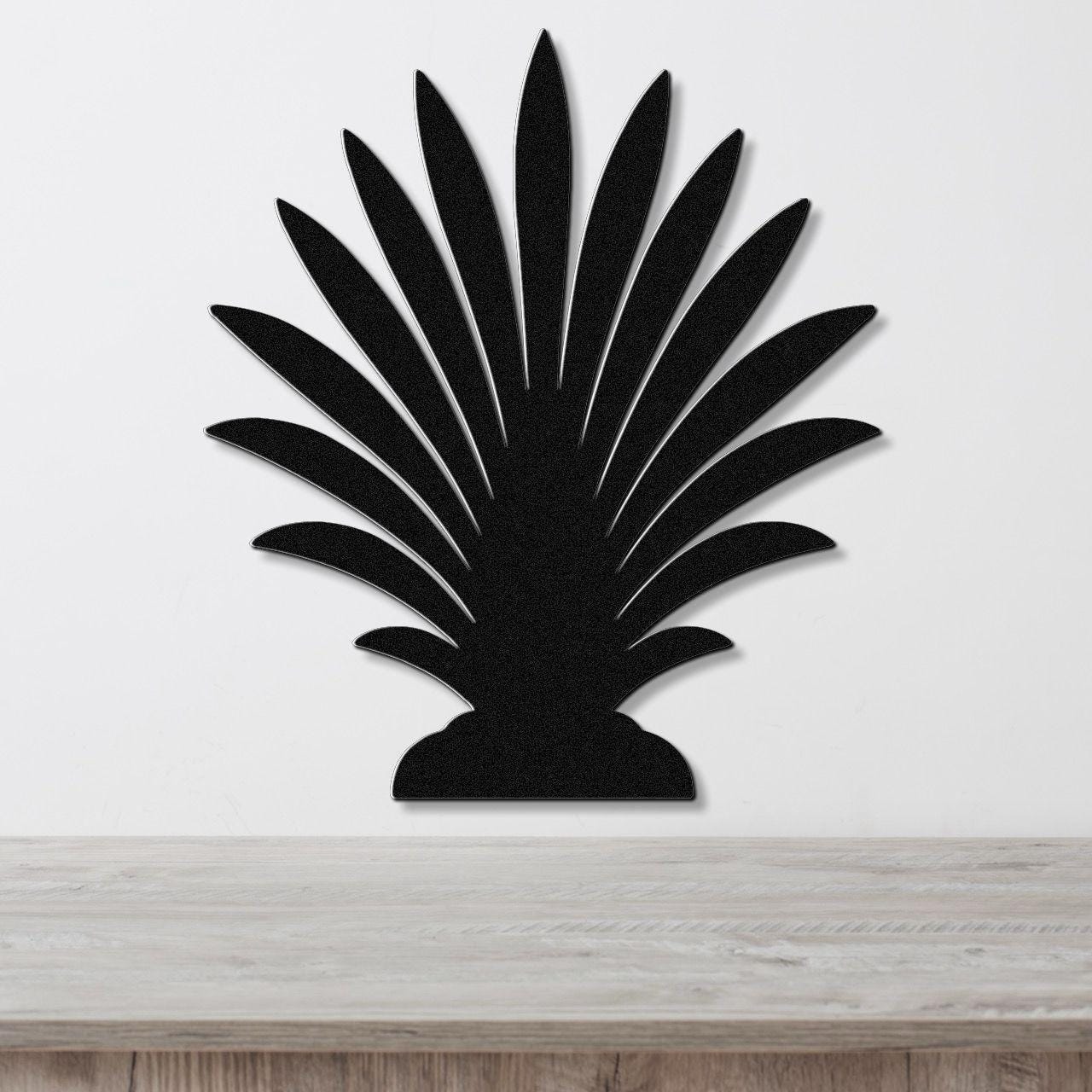 Black metal palm tree wall art with layered leaf cutouts, mounted on a white wall above a light wood countertop.