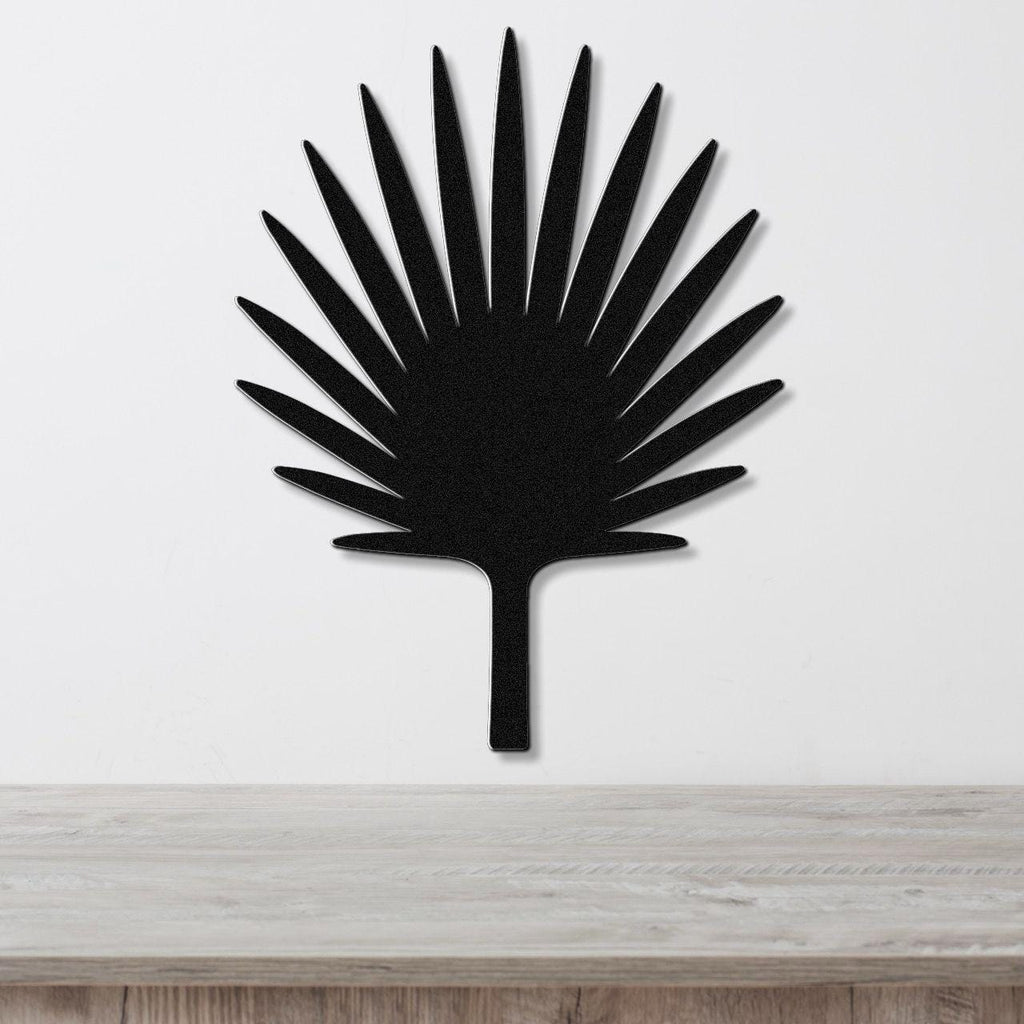 Black metal fan palm tree wall art with radiating leaf cutouts, mounted on a white wall above a light wood surface.