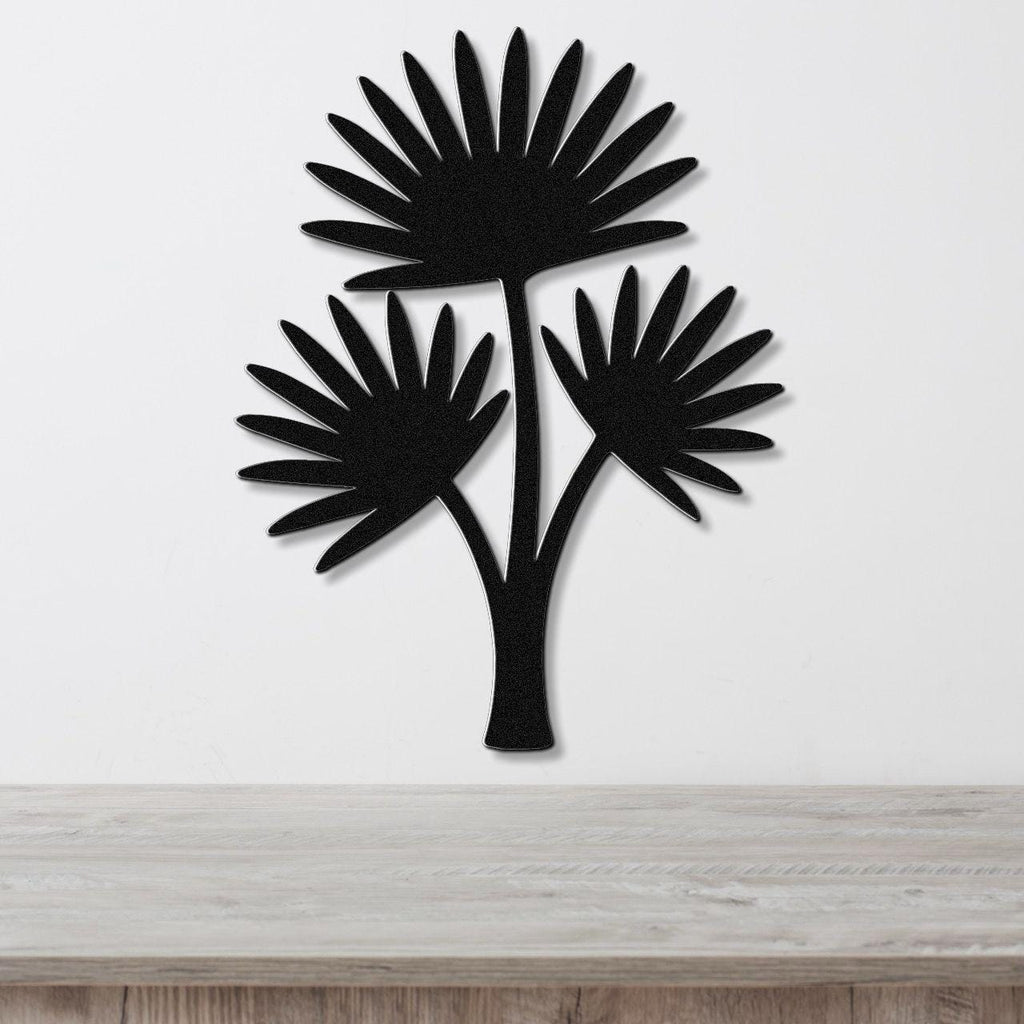 Black metal cutout wall art of a fan palm tree with three fronds, mounted on a white wall above a light wood countertop.