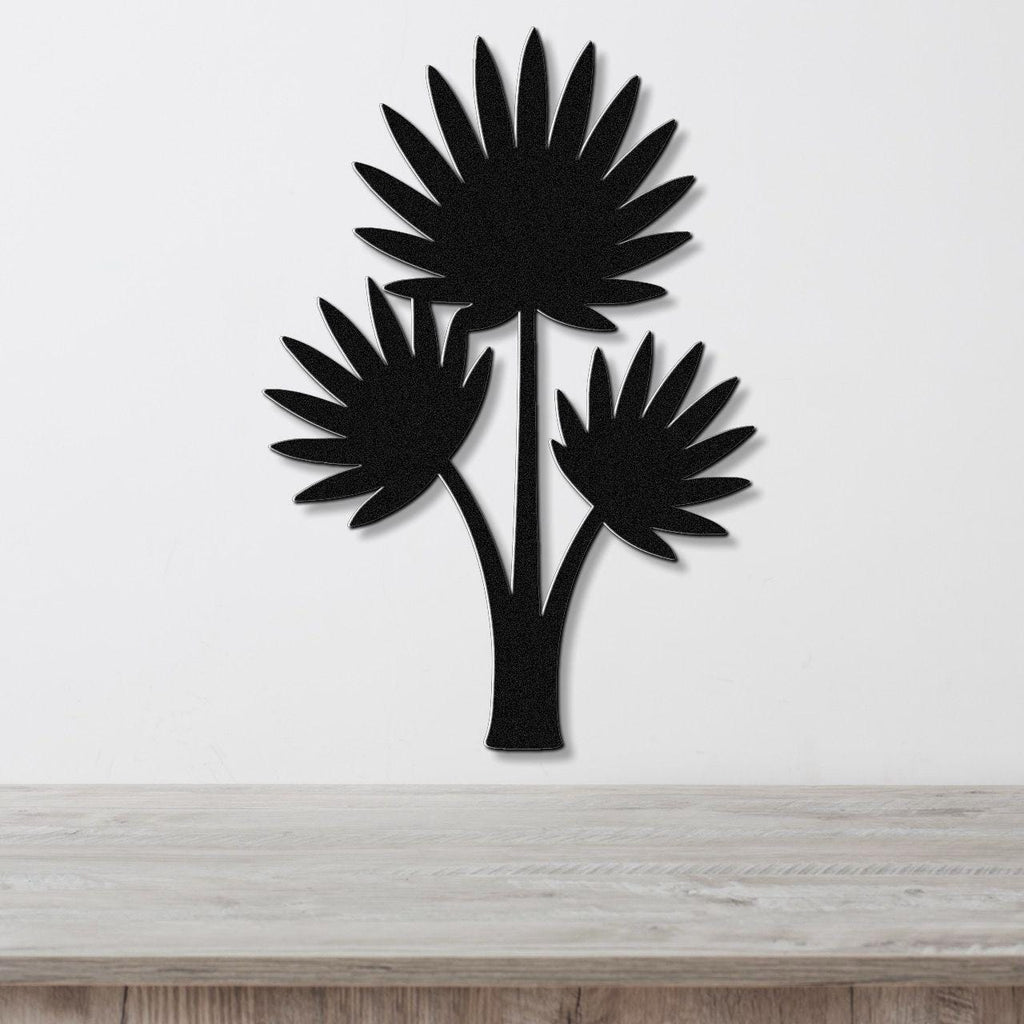 Black metal wall art silhouette of a fan palm tree with three fronds, mounted on a white wall above a light wood surface.
