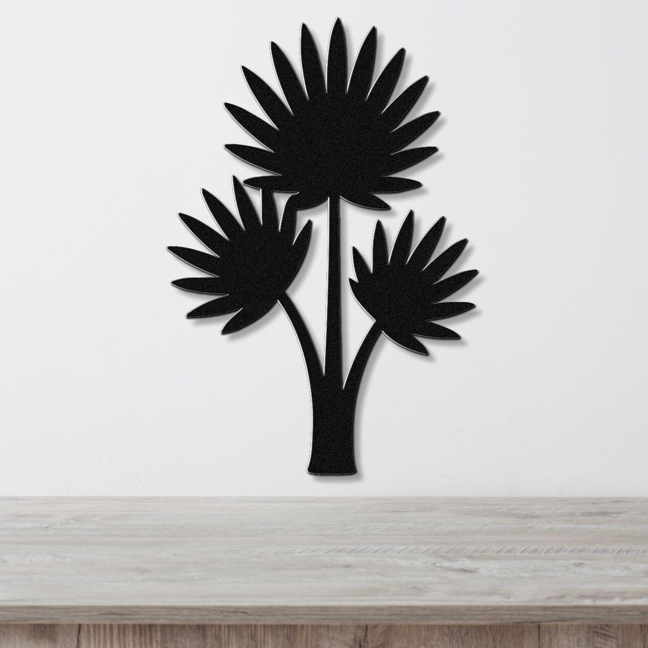 Black metal wall art silhouette of a fan palm tree with three fronds, mounted on a white wall above a light wood surface.