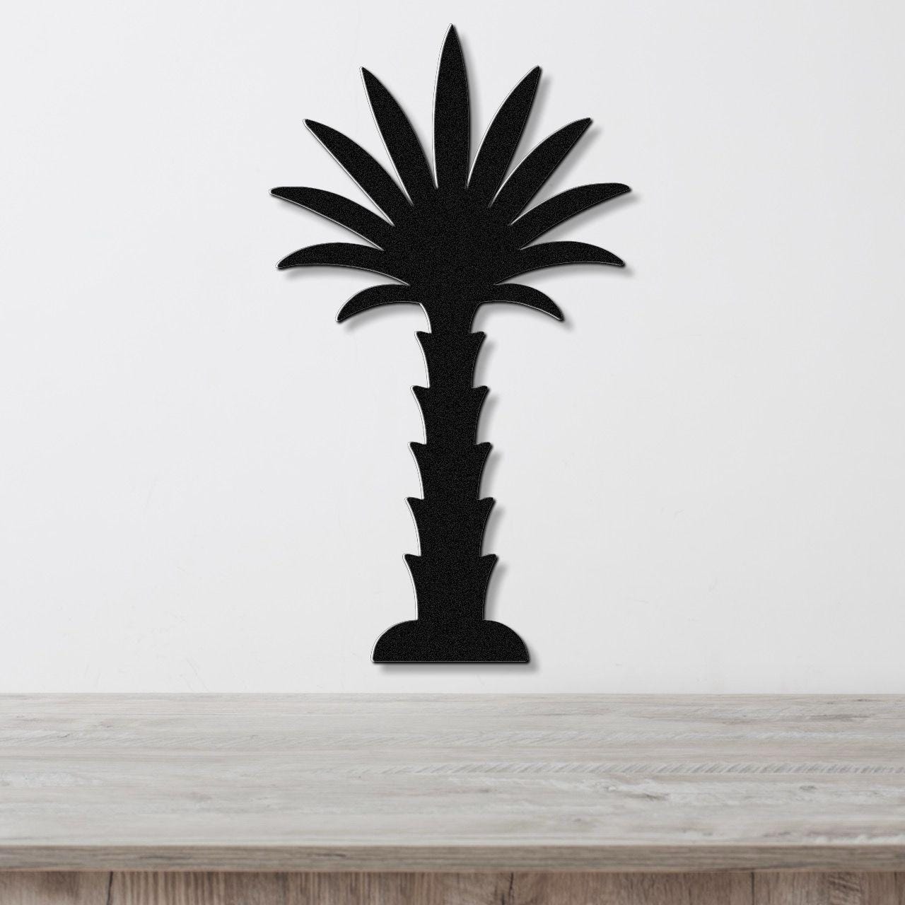 Black metal palm tree wall art with a silhouette cutout design, mounted on a white wall above a light wood countertop.