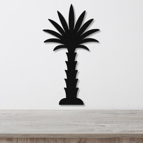 Black metal palm tree wall art with a silhouette cutout design, mounted on a white wall above a light wood countertop.