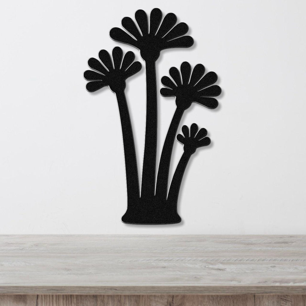 Black metal wall art cutout of three fan palm trees, mounted on a white wall above a light wood surface.