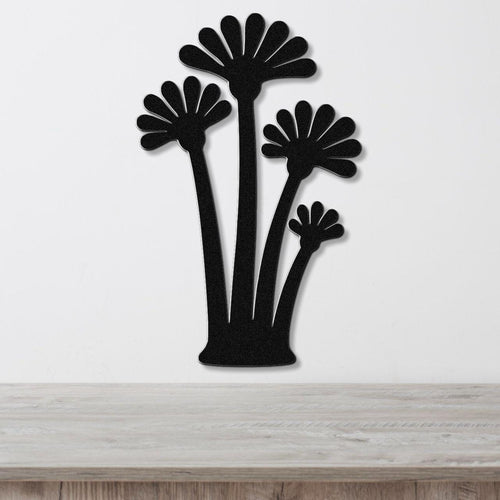 Black metal wall art cutout of three fan palm trees, mounted on a white wall above a light wood surface.