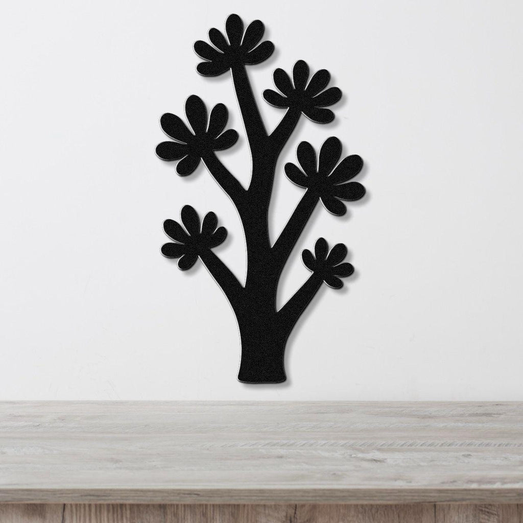 Black metal wall art in a tree silhouette with flower cutouts, mounted on a white wall above a light wood counter.