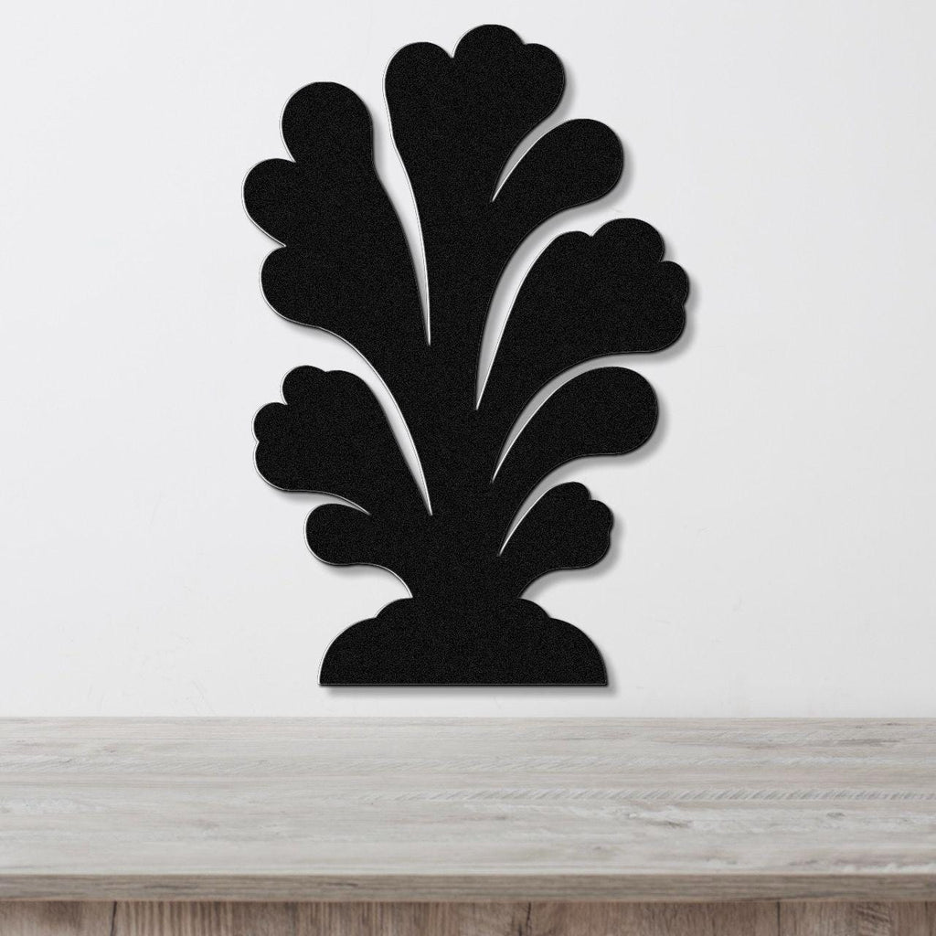 Black metal wall art in a coral silhouette design with layered, flowing cutouts, mounted on a white wall above a wooden surface.