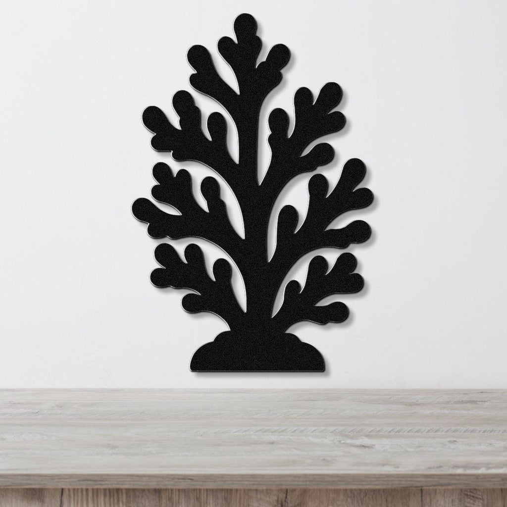 Black metal coral wall art with branching cutouts, mounted on a white wall above a light wood counter.