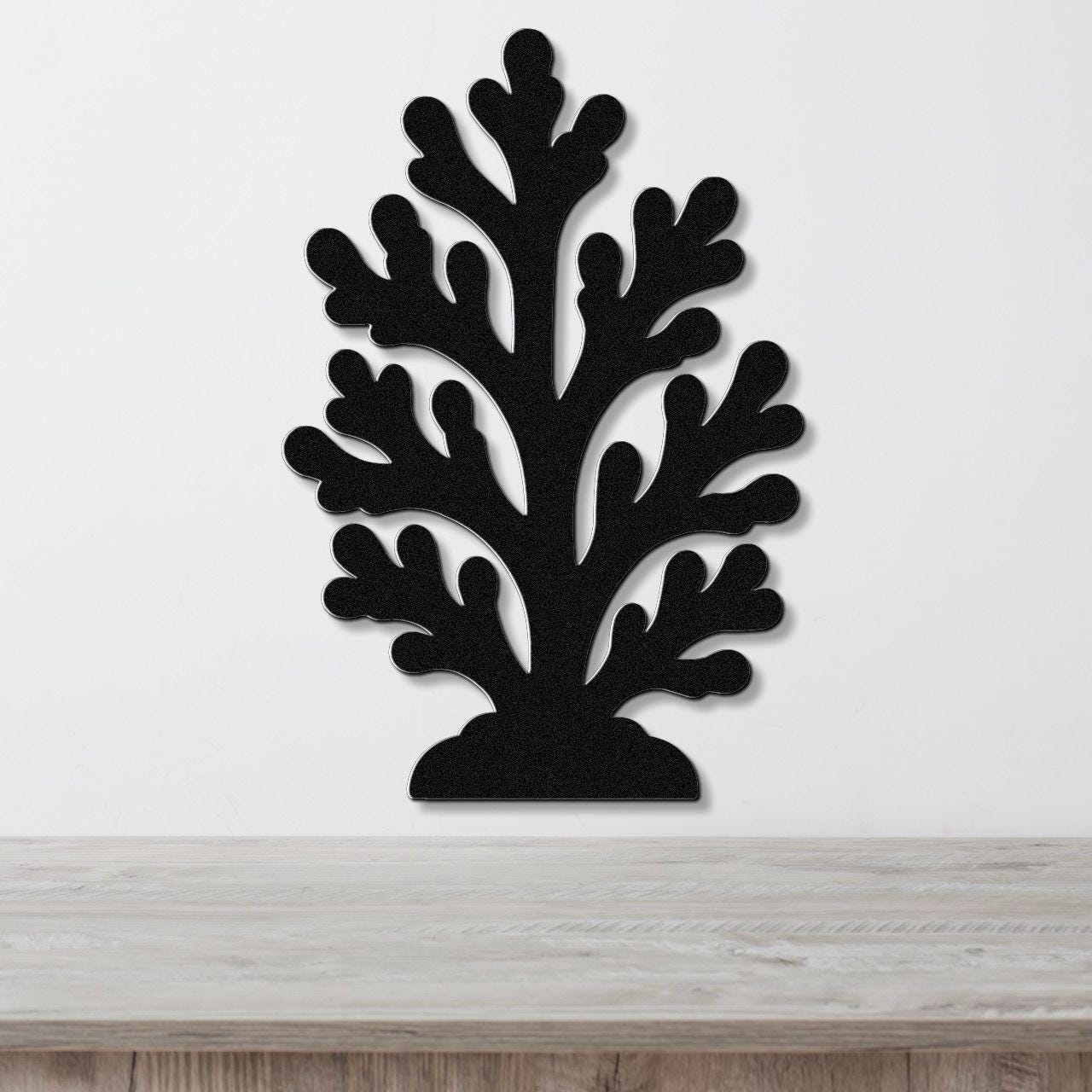 Black metal coral wall art with branching cutouts, mounted on a white wall above a light wood counter.
