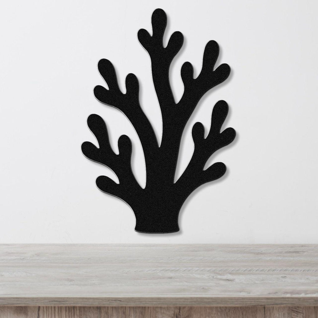 Black metal wall art in a branching coral silhouette with multiple cutout arms, mounted on a white wall above a light wood surface.