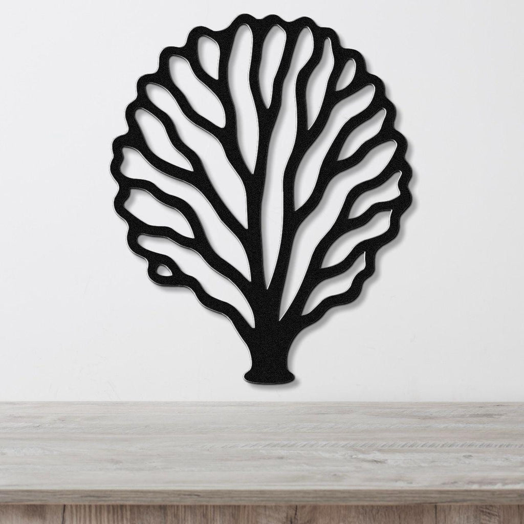 Black metal fan coral wall art with intricate cutout branches, mounted on a white wall above a light wood counter.