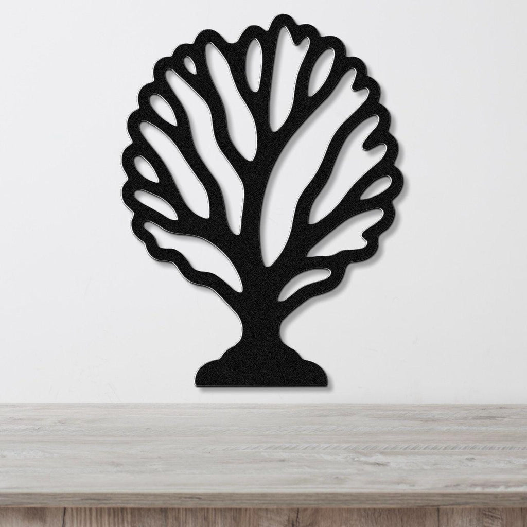 Black metal wall art in a fan coral silhouette with intricate branching cutouts, mounted on a white wall above a light wood surface.