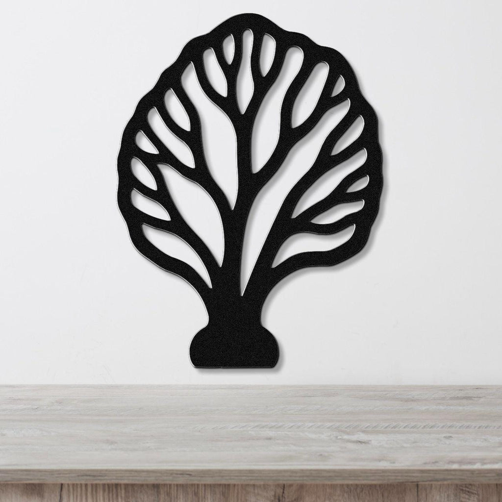 Black metal wall art in a fan coral silhouette with intricate internal cutouts, mounted on a white wall above a light wood surface.
