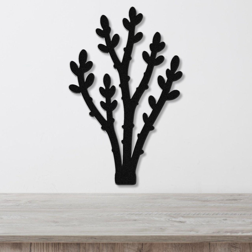 Black metal wall art in a desert branch silhouette design, mounted on a white wall above a light wood countertop.