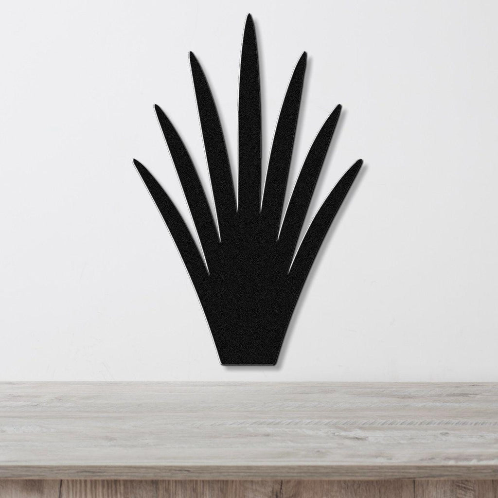Black metal yucca wall art with pointed leaf cutouts, mounted on a white wall above a light wood surface.