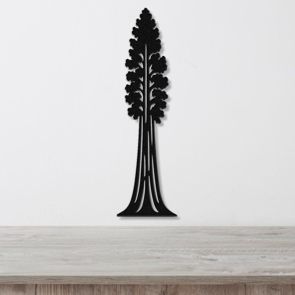 Black metal wall art in the silhouette of a sequoia tree with detailed branch cutouts, mounted on a white wall above a light wood surface.