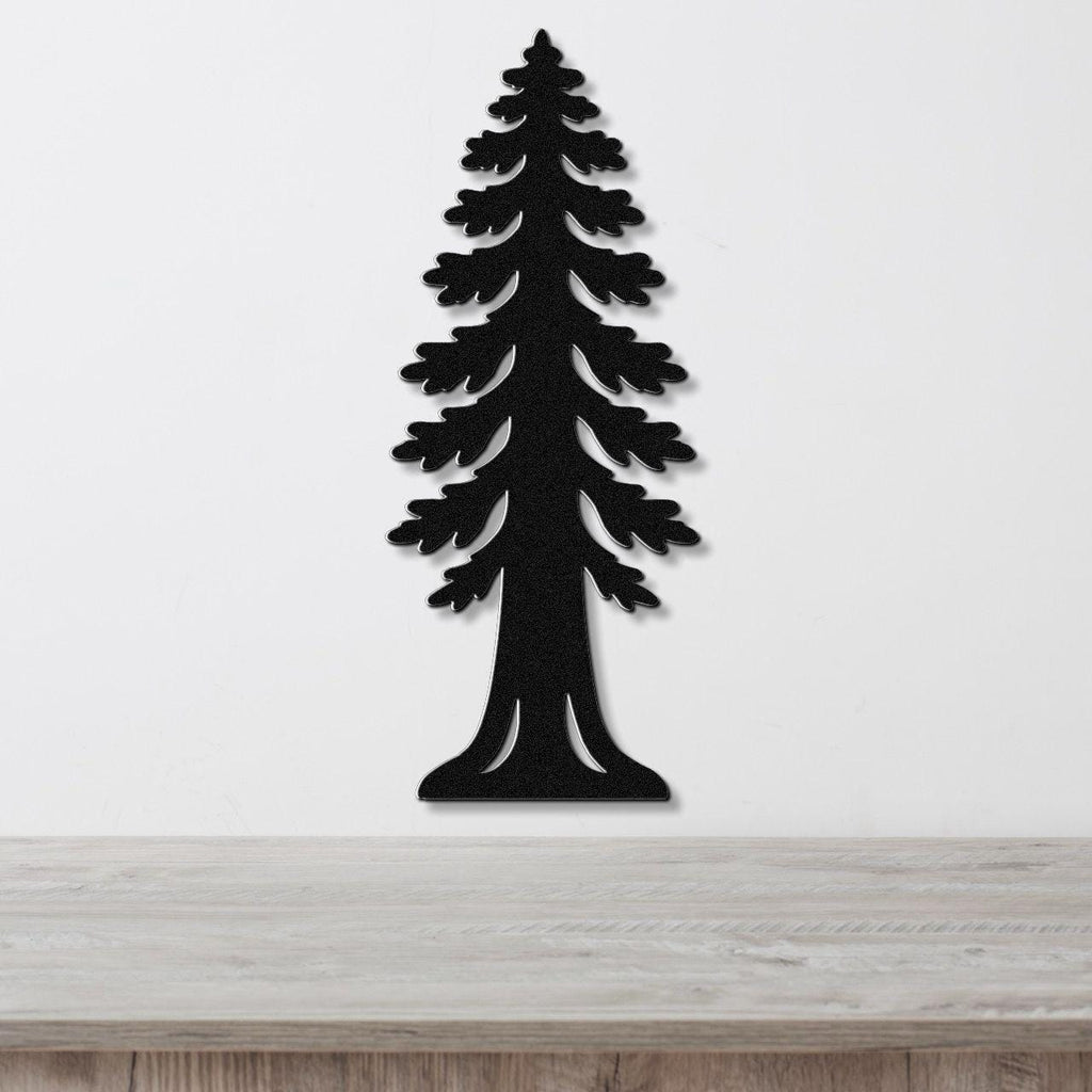 Black metal wall art cutout of a sequoia tree with layered branches and a wide base, mounted on a white wall above a light wood surface.