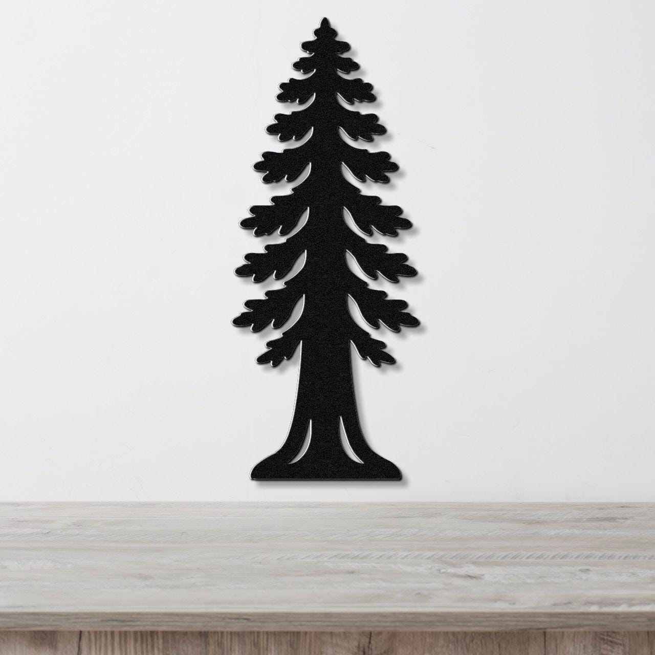 Black metal wall art cutout of a sequoia tree with layered branches and a wide base, mounted on a white wall above a light wood surface.