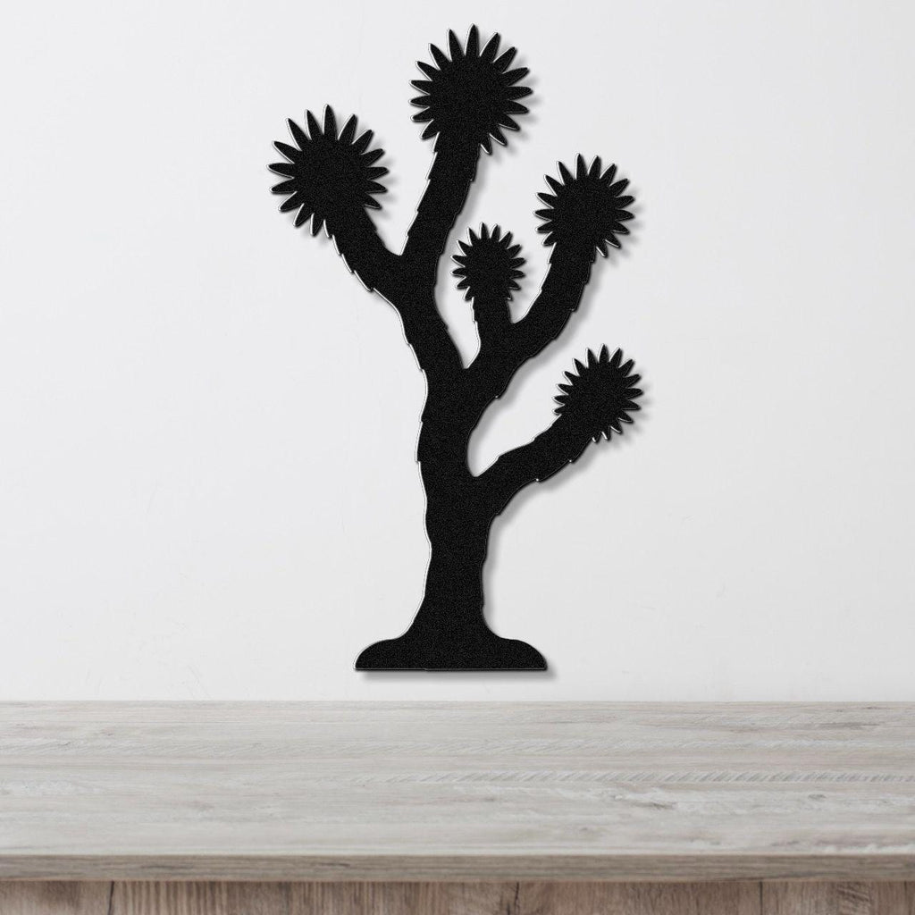 Black metal Joshua tree wall art with starburst-shaped branches, mounted on a white wall above a light wood countertop.