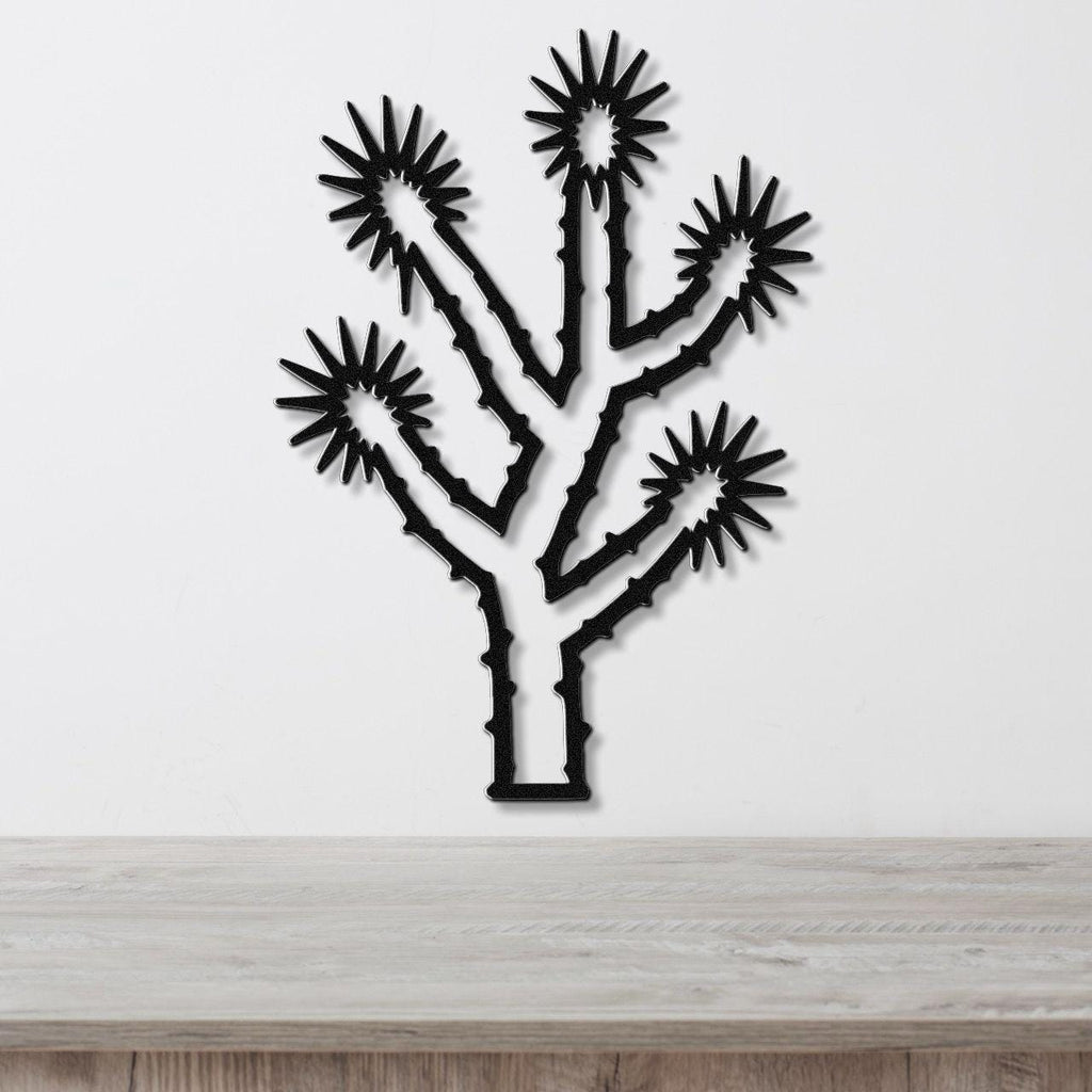Black metal Joshua tree wall art with starburst cutouts, mounted on a white wall above a light wood counter.