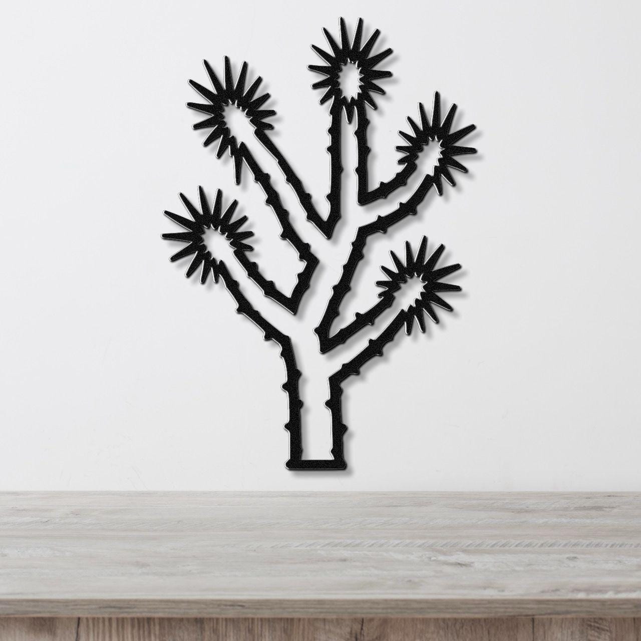 Black metal Joshua tree wall art with starburst cutouts, mounted on a white wall above a light wood counter.