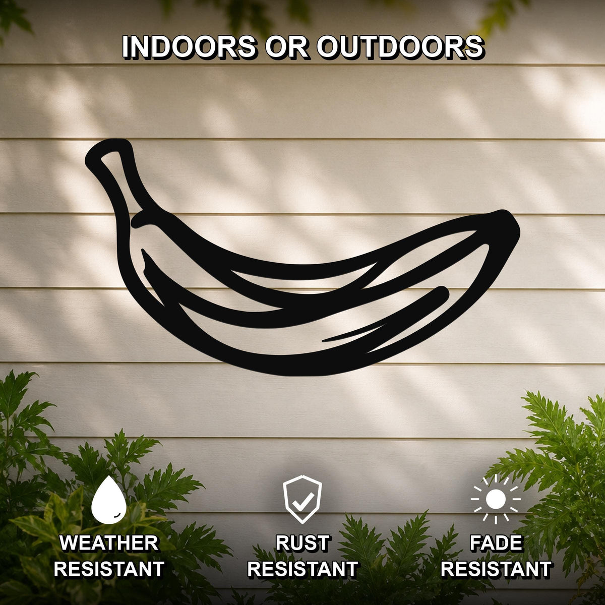 Black metal banana wall art silhouette mounted on a light-colored outdoor wall, with green plants at the base and text indicating it is weather, rust, and fade resistant.