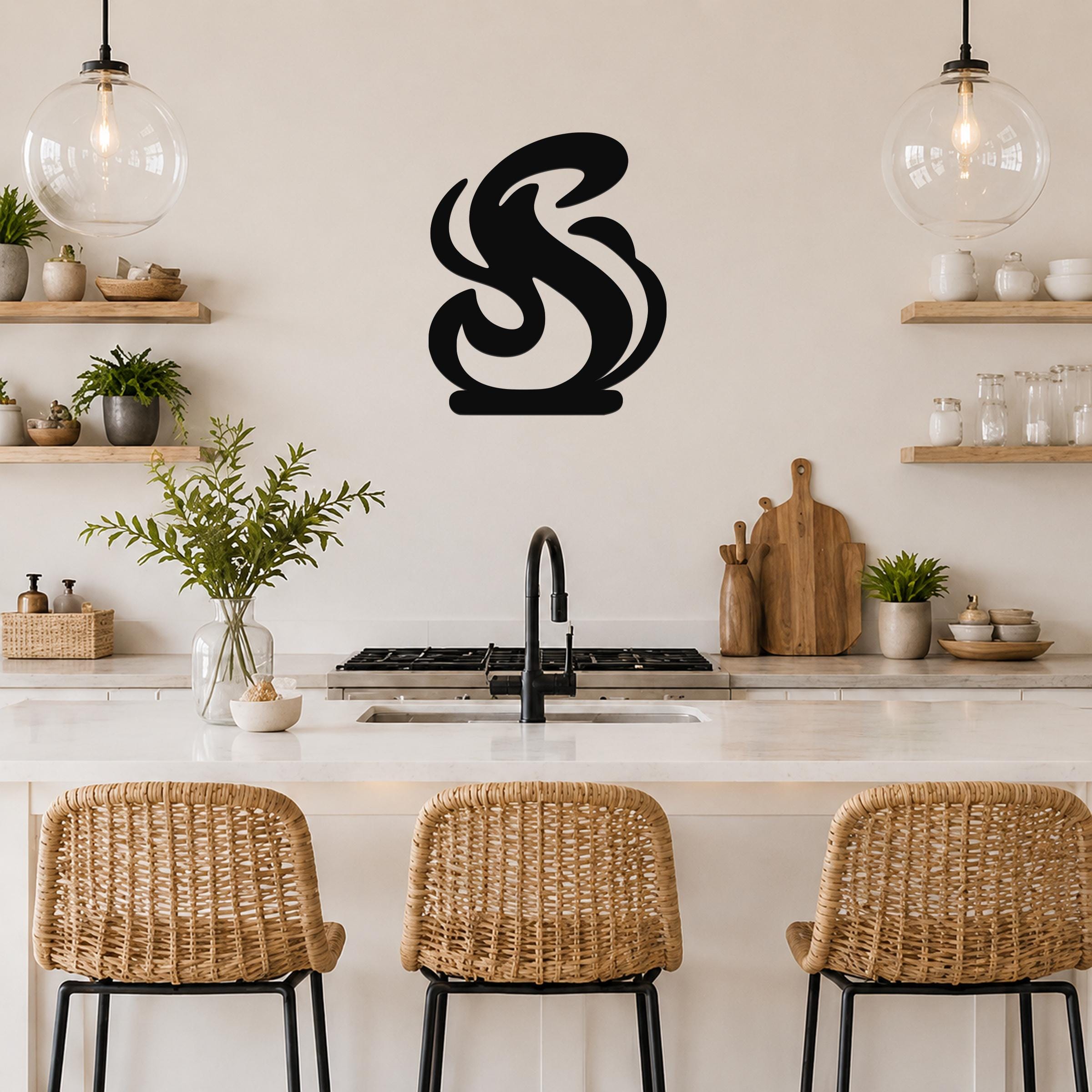 Black metal wall art in a flowing flame silhouette, mounted on a kitchen wall above a counter with wicker bar stools.