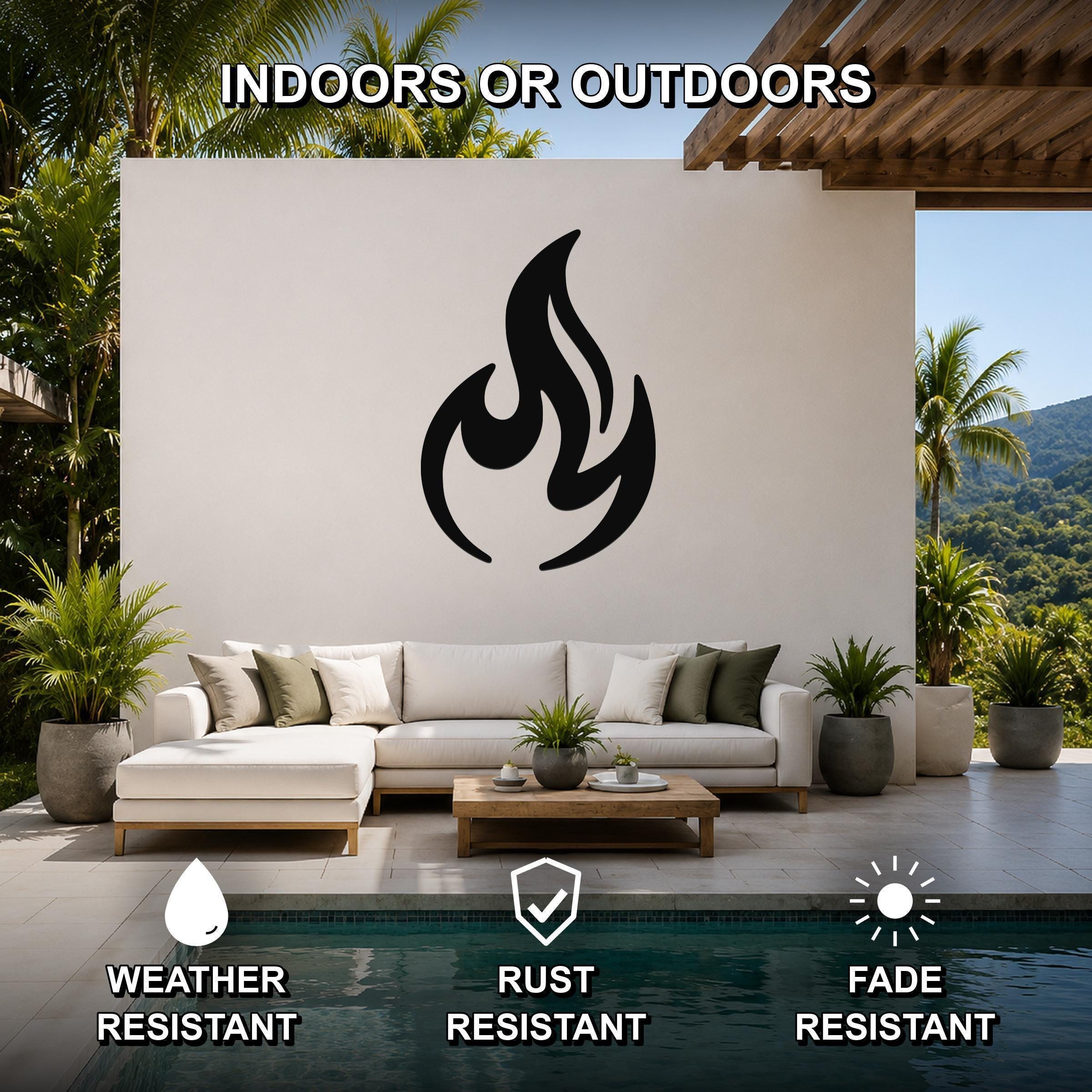 Black metal flame silhouette wall art mounted on a white outdoor wall above a white sectional sofa in a patio living area.
