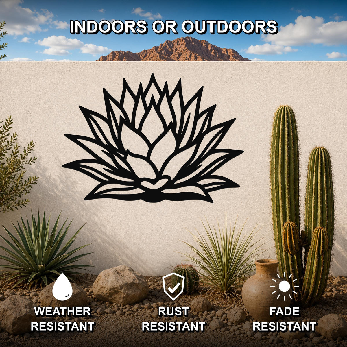 Black metal agave wall sculpture with leaf cutouts, mounted on a white outdoor wall in a desert garden setting.