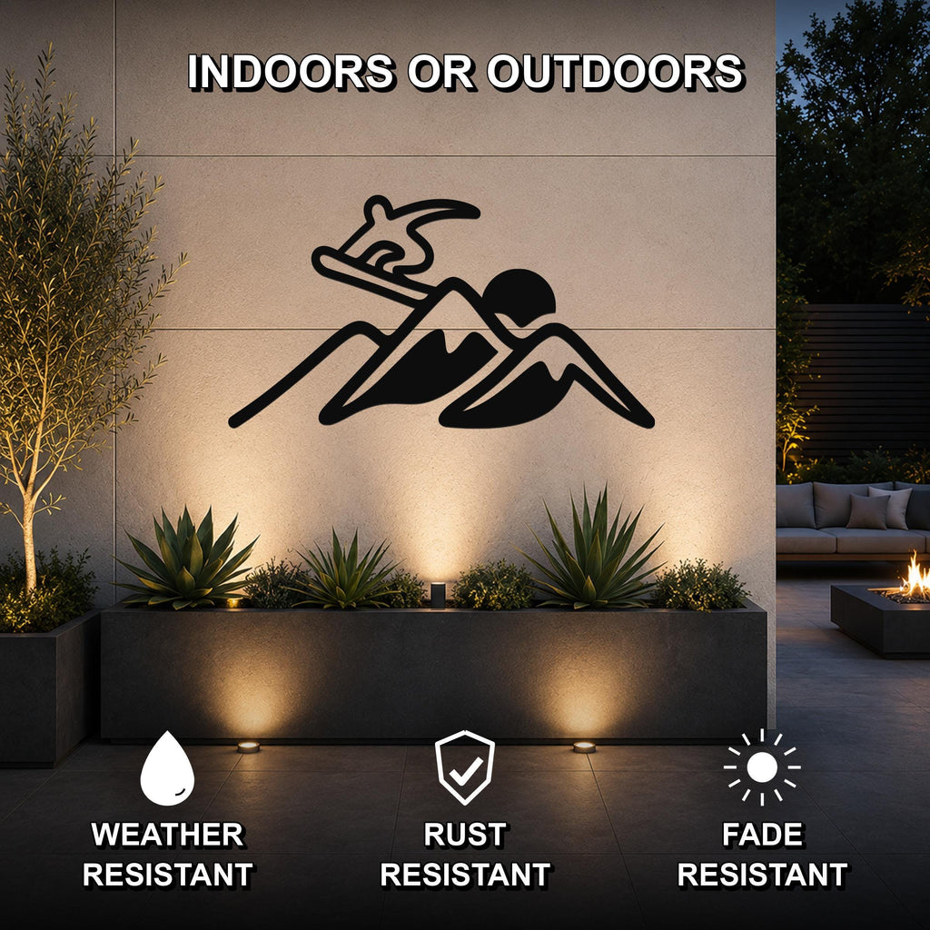 Black metal wall art silhouette of a snowboarder above mountains, mounted on an outdoor wall above a planter with succulents, in a modern patio setting.