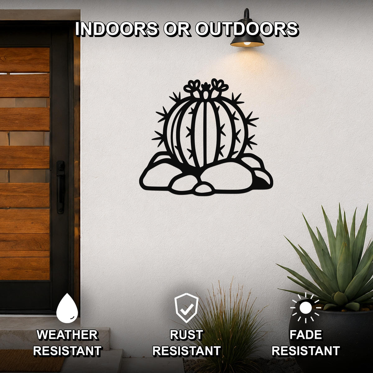 Black metal barrel cactus wall art with spines and flower cutouts, mounted on a white outdoor wall beside a wooden door.